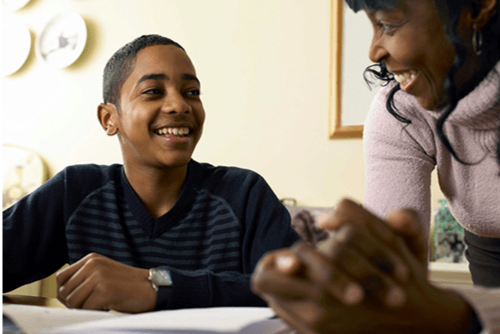 Mother and son smiling while doing homework